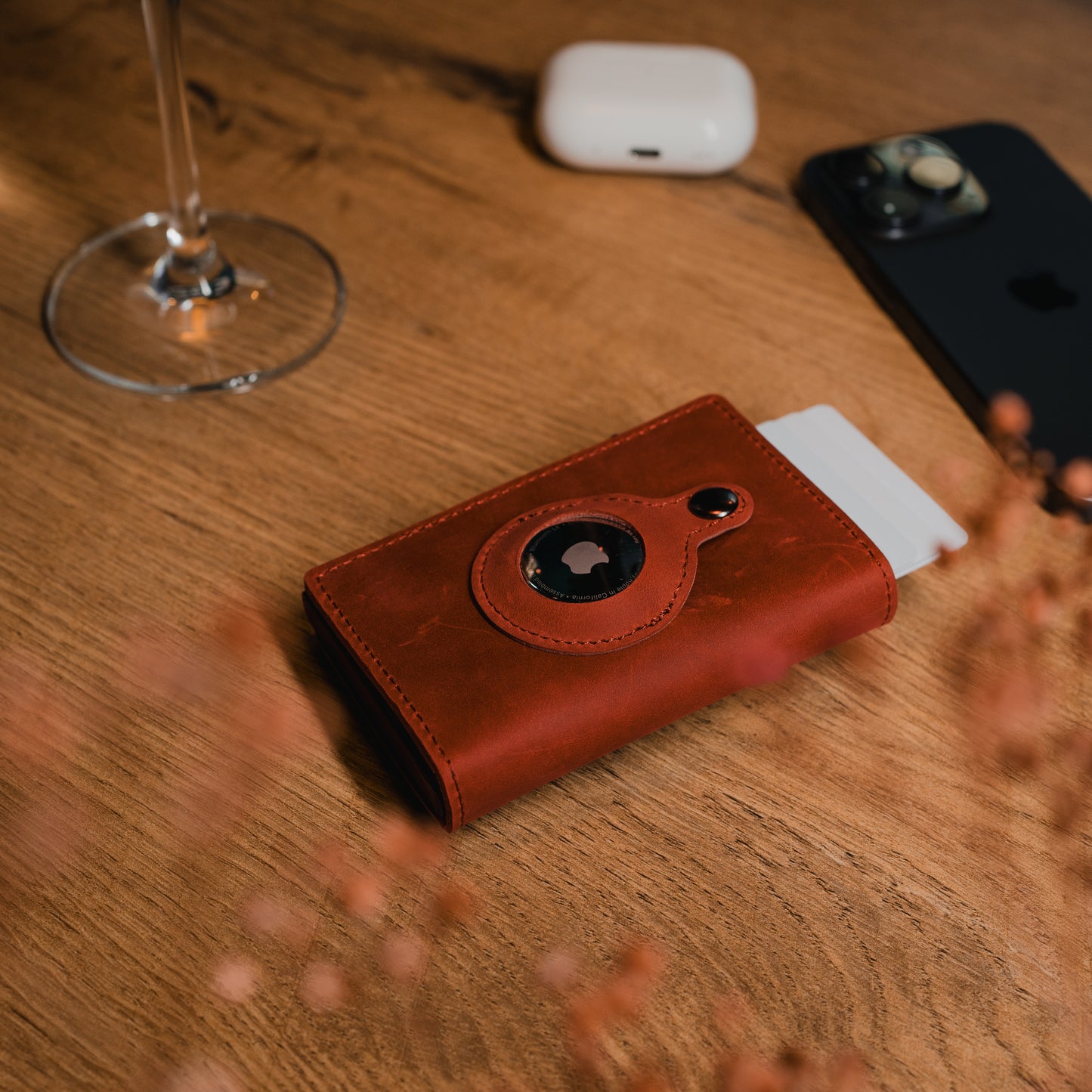 Luxuriöses Smart Wallet in Weinrot auf Holztisch. Hochwertiges Echtleder, RFID-Blocker und praktisches Fach für einen AirTag.